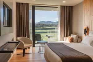 a hotel room with a bed and a large window at Pedras do Mar Resort & Spa in Fenais da Luz