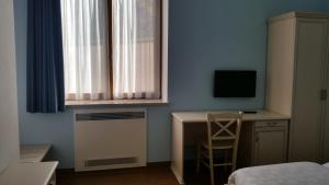 a bedroom with a desk and a television and a bed at Agritur Maso Barco in Faedo