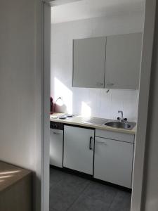 a kitchen with white cabinets and a sink at My Home Location in La Chaux-de-Fonds