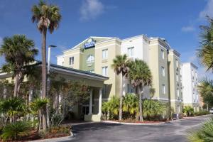 a hotel with palm trees in front of a building at Days Inn & Suites by Wyndham Fort Pierce I-95 in Fort Pierce