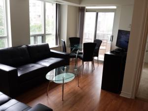 a living room with a black couch and a glass table at 2 Bedroom 1 Bathroom Prime Location in Mississauga in Mississauga