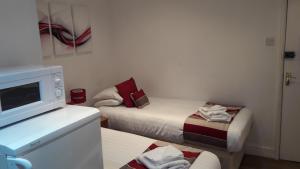 a small room with two beds and a microwave at Alexandra Guest House in Hemel Hempstead