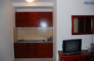 a kitchen with wooden cabinets and a tv at Apartments Krapina in Budva +36 photos