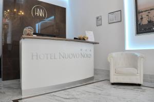 Un cartel del Hotel Novo Nord en un mostrador junto a una silla. en Hotel Nuovo Nord, en Génova