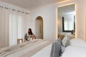 a woman standing in a bedroom with two beds at Apollon Boutique Hotel in Parikia