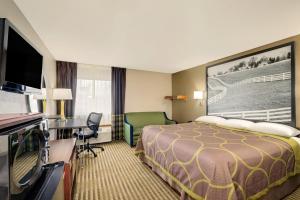 a hotel room with a bed and a desk and a television at Super 8 by Wyndham Lexington Hamburg Area in Lexington