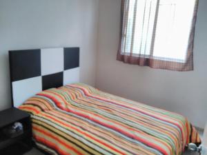 Una cama con una manta de rayas de colores en un dormitorio en Casa en Real Santa Fe en Xochitepec