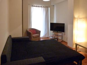 a living room with a couch and a chair and a television at Homely Spacious Studio in Chalkida