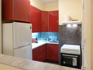 a kitchen with red cabinets and a white refrigerator at Homely Spacious Studio in Chalkida