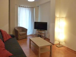 a living room with a couch and a tv and a table at Homely Spacious Studio in Chalkida