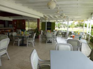 un restaurante con sillas, mesas, mesas y sillas en Rockley Golf Club, 2 bed 2 bath Pool, Tennis, Golf, Bar & Restaurant!, en Bridgetown