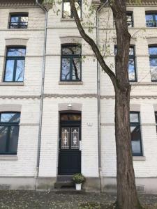 un edificio de ladrillo blanco con una puerta negra y un árbol en Apartment KR18, en Ratingen