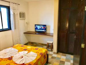 um quarto de hotel com duas camas e uma televisão em Pousada Icaraí em Ilha Comprida