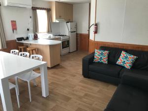 a living room with a black couch and a kitchen at Toora Tourist Park in Toora