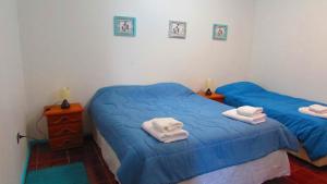two beds in a room with blue sheets and towels at Hostal Casa Azul in Talca
