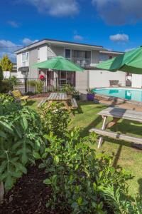 un patio con mesas de picnic y una piscina en Continental Motel, en Whangarei