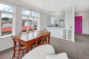 una cucina e una sala da pranzo con tavolo e sedie di Spacious Sunny Seaview Apartment ad Auckland