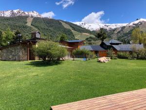 dom z zielonym ogródkiem z górami w tle w obiekcie Complejo Mil50 w mieście Bariloche