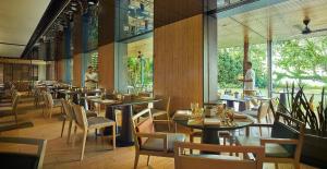 a restaurant with tables and chairs and people in the background at PARKROYAL Penang Resort in Batu Ferringhi