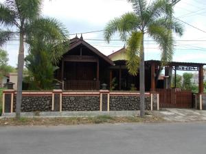 a house with palm trees in front of it at Jati Classic Homestay in Banyuwangi