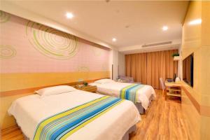 HelixiにあるGreenTree Inn AnHui Ningguo Ningguo Avenue Business Hotelのベッド2台とテレビが備わるホテルルームです。
