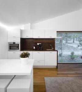 a kitchen with white cabinets and a white table at Pedras Salgadas Spa & Nature Park in Pedras Salgadas