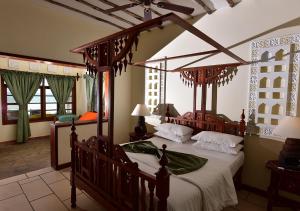a bedroom with a canopy bed with white sheets at Kilifi Bay Beach Resort in Kilifi +39 photos