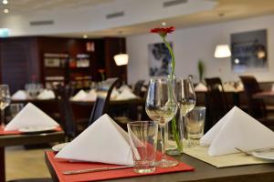 a table with glasses and a vase with a flower on it at Michel Hotel Wetzlar in Wetzlar