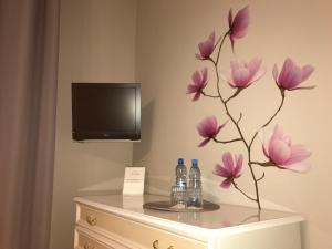 Zimmer mit einem TV und Blumen auf der Kommode in der Unterkunft Apartament czteroosobowy z tarasem in Warschau