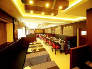 um restaurante com mesas longas e cadeiras vermelhas em Hotel A J Park em Alappuzha