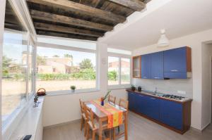 a kitchen with blue cabinets and a table with chairs at Villa Pasquale...immersa nella tranquillita' in Lascari +10 photos