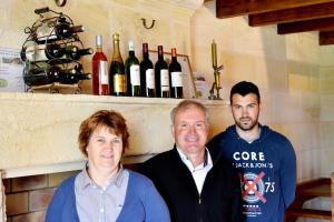 three people standing in front of a shelf of wine bottles at Chateau Laborde Marjolaine in Saint-Médard-de-Guizières