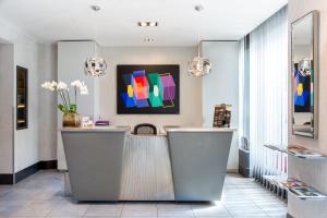 a lobby with a counter with a painting on the wall at Porte de Versailles Hotel in Paris