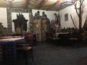 a restaurant with tables and chairs and a stone wall at Pensiunea Cascada in Comăneşti