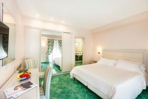 a bedroom with a white bed and a green floor at Hotel Continental Ischia in Ischia