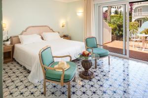 a bedroom with a bed and two chairs and a table at Hotel Continental Ischia in Ischia