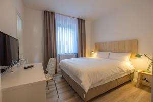 a bedroom with a bed and a desk and a television at Hotel Cityroom in Gelsenkirchen