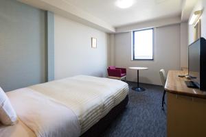 a hotel room with a bed and a desk and a television at Comfort Inn Niigata Kameda in Niigata