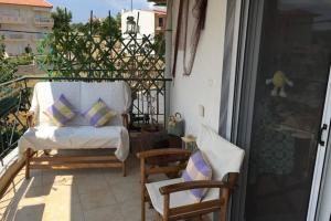 a balcony with a chair and a couch on a patio at Isabelle's apartment in Kallithea Halkidikis