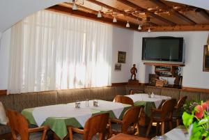 a dining room with two tables and a flat screen tv at Frühstückspension Kirchenwirt in Obervellach