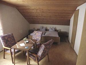 Steinbach am WaldにあるPension Löfflerのベッド、テーブル、椅子が備わる客室です。