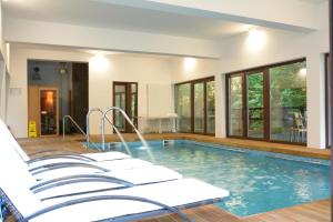a swimming pool with white chairs in a house at Gasthaus Grindeshti in Văliug
