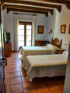 a hotel room with three beds and a television at Hotel Rural Castúo H CC 656 in Pinofranqueado