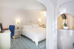 a bedroom with a white bed and a desk at Hotel Continental Ischia in Ischia
