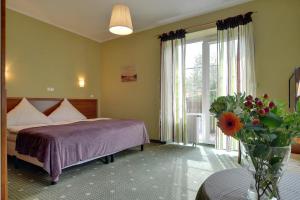 1 dormitorio con 1 cama y un jarrón de flores en Hotel Belweder - przy hotelu Golebiewski, en Karpacz