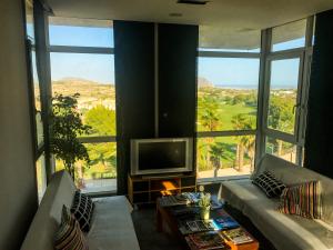 a living room with a television and large windows at 01 Loft Alenda Golf in Monforte del Cid