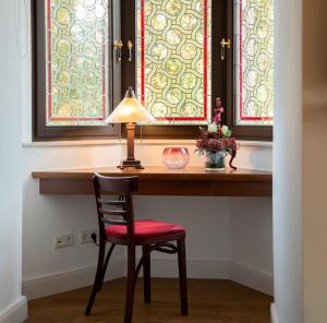 einen Schreibtisch mit einem Stuhl und einer Lampe sowie zwei Fenster in der Unterkunft Pension VILLA KLEINE WARTBURG in Eisenach + 32 Fotos