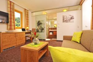 a living room with a couch and a tv at Hotel Barbarahof Saalbach in Saalbach Hinterglemm