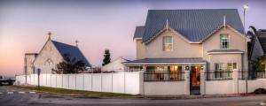 una casa con una recinzione bianca e una chiesa di 23 On Glen Guest House a Port Elizabeth
