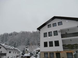 a white building with black windows in the snow at Apartman Aya in Janov nad Nisou